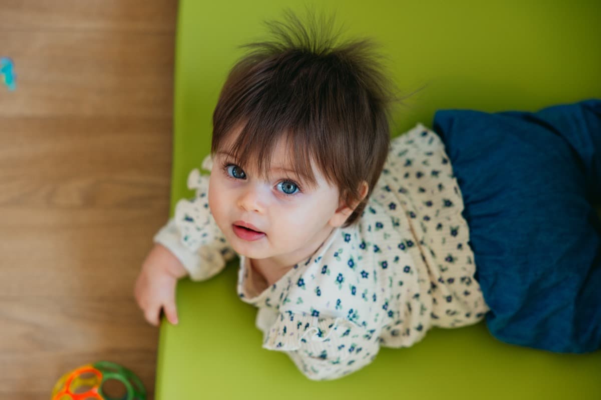 Bébé allongé sur un tapis vert à la crèche Chez Maï
